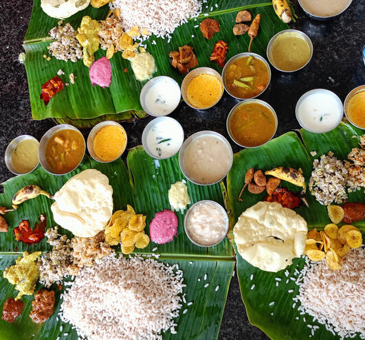 Click here for Sweet Earth Goa Guide Traditional thali meal served on banana leaves with rice, curries, and sides.